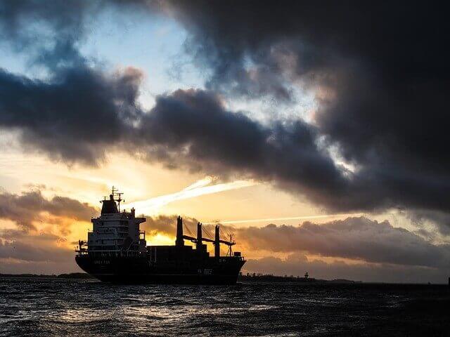 cargo ship on water at sunset